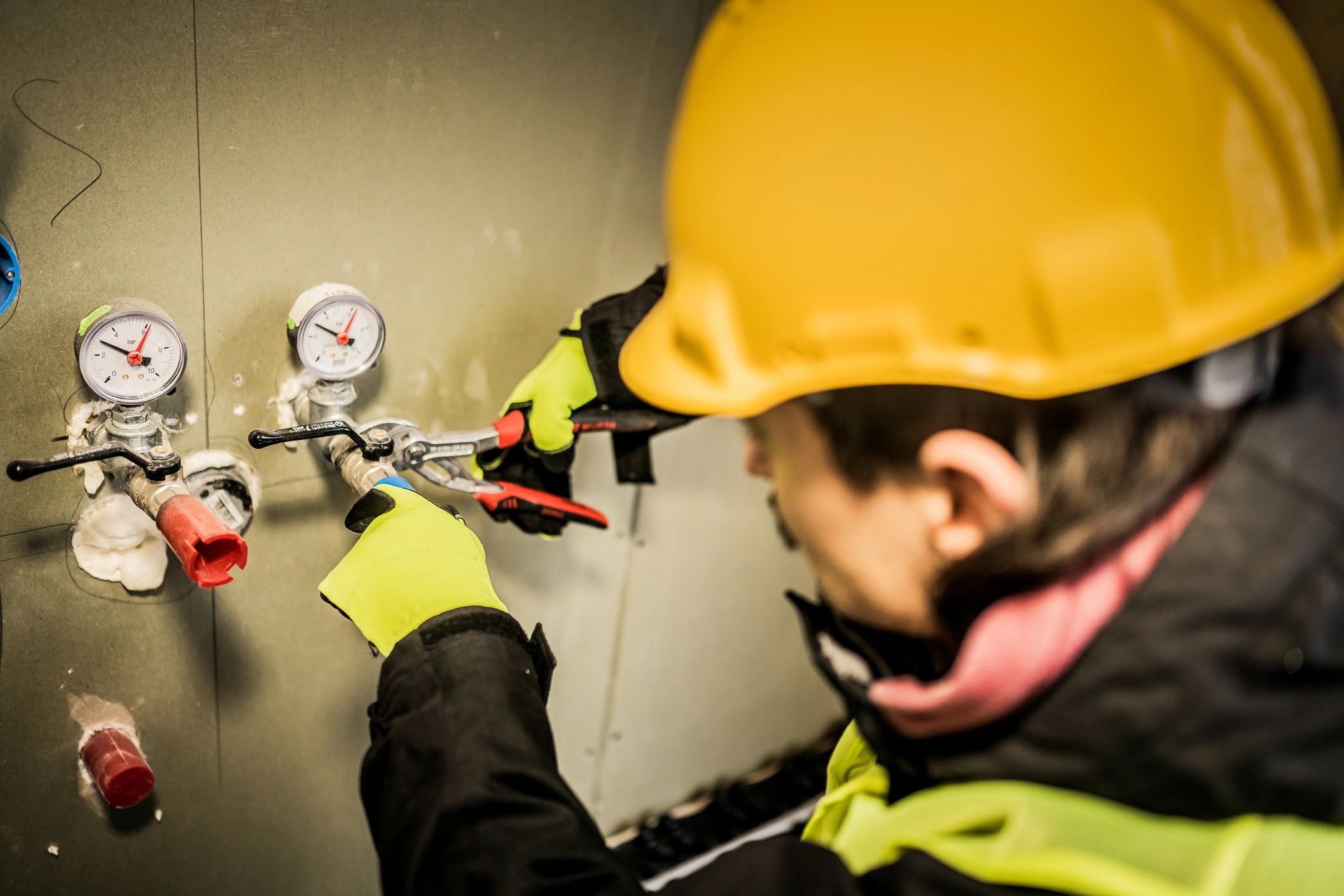 Plumber working on water pipes with hand tools